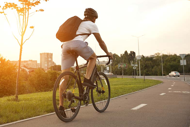Young guy in casual clothes is cycling on the road in the evening city
