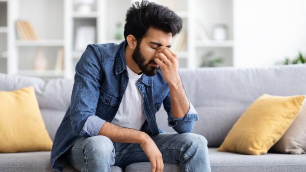 south asian man depressed sitting on couch